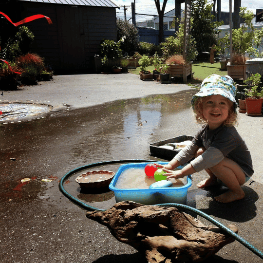 Zesty Virtual Assistants ECE admin, Early Childhood Admin for childcare centres. Child playing with water in a bowl in a garden