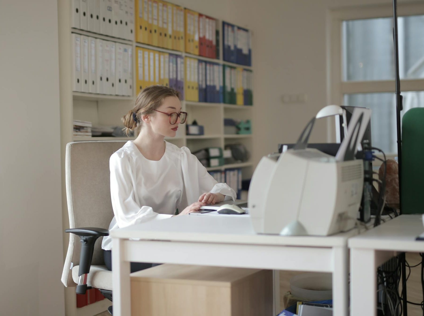 Zesty for Early Childhood Education 2 Focused woman working in a modern office filled with files and equipment.